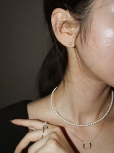 Detailed view of 925 sterling silver pearl necklace and crescent moon pendant on model