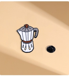 Close-up of a white and brown cartoon moka pot enamel pin with a black butterfly clutch