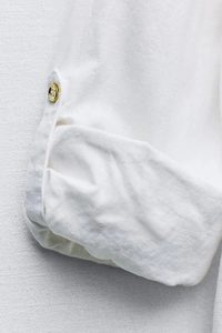 Detailed macro view of white linen shirt cuff with adjustable button tab design
