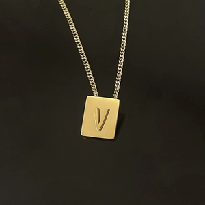 Macro shot of 18K gold-plated stainless steel rectangular pendant with embossed letter V