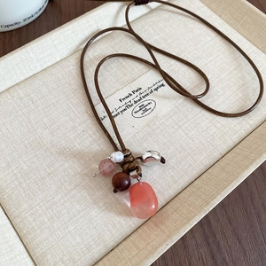Detailed shot of pink stone pendant with wooden bead on ethnic wax rope necklace