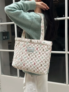 Quilted white tote bag with floral teddy bear print and blue studio label on shoulder