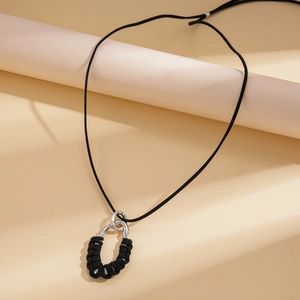 Detail of silver irregular metal ring with black cord weaving on velvet rope necklace