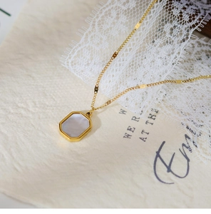 Close-up of 18K gold plated necklace with octagonal white shell pendant on lace