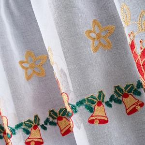 Close-up of Christmas embroidery on sheer white curtain with bells and holly leaves