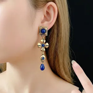 Vintage floral tassel earrings with blue gemstones and gold finish on Asian model