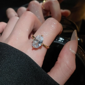 Close-up of a gold oval zircon ring with elegant four-prong setting on a model's finger