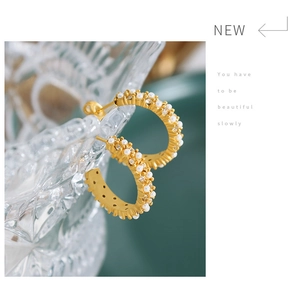 Détail de boucles d'oreilles créoles dorées 18K avec micro-perles et zircons