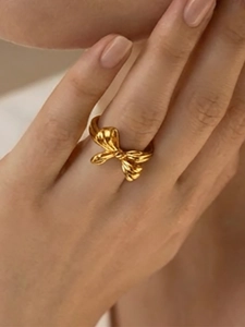 Detailed close-up of a 18k gold plated stainless steel bow ring on a woman finger