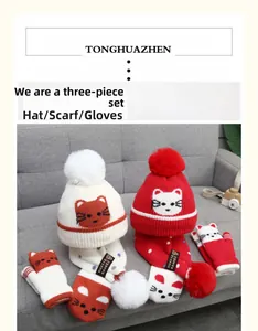 Detail view of kids winter set featuring knitted hat with cartoon cat and pom-poms