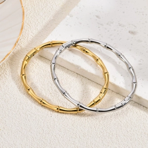 Detail von 18K gold- und silberplattierten Bambus-Armreifen auf strukturiertem Stein