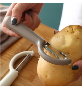 Action shot of the stainless steel peeler removing skin from a fresh potato