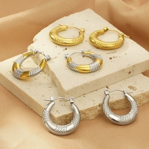 Detail of 18K gold and silver U-shaped hoop earrings with textured snake pattern
