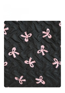 Close-up of black quilted fabric featuring elegant pink bow patterns and textures