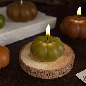 Macro view of lit pumpkin-shaped candles on wood tray for autumn home decor
