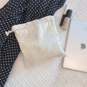 Close-up of white floral lace embroidery on a cotton drawstring storage bag