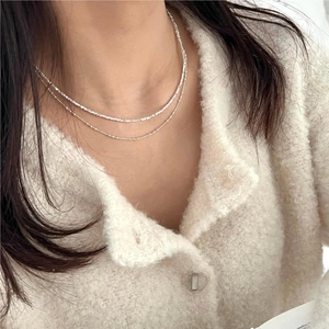 Detail of minimalist 925 sterling silver double-layered beaded necklace on a model's neck