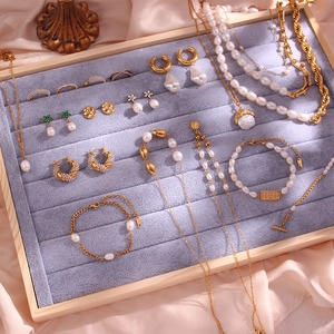Elegant gold titanium steel jewelry set with white pearls on a velvet display tray