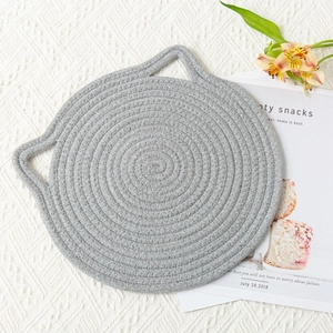 Detailed top view of a grey cat-ear shaped woven cotton placemat on a cozy home setting