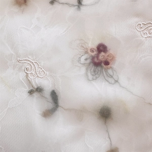 Detailed view of floral embroidery on a white mesh shoulder bag showing pink flowers