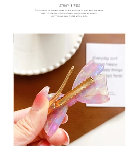 Detail view of the golden metal clip on the back of the purple acetate bow hairpin