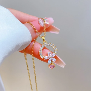 Detailed shot of golden floral pendant necklace with sparkling pink gemstone and zircon