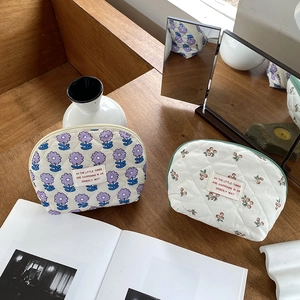 Quilted floral and cherry makeup bags on a wooden table in a natural light setting
