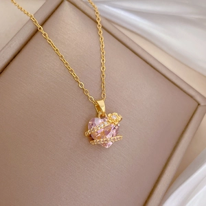 Macro view of gold chain necklace with pink heart gemstone and diamond-set floral detail