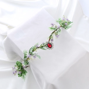 Close-up of a floral crown featuring a red teardrop crystal and green leafy vines