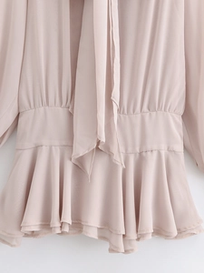 Detail of nude pink chiffon dress featuring elastic waist and layered ruffle hemline