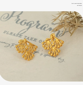 Close-up of golden branch shaped stud earrings with high gloss finish on art paper