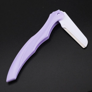 Purple folding eyebrow razor with stainless steel safety blade on a dark background