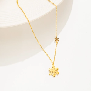 Minimalist 18K gold plated snowflake pendant necklace displayed on a white ceramic plate