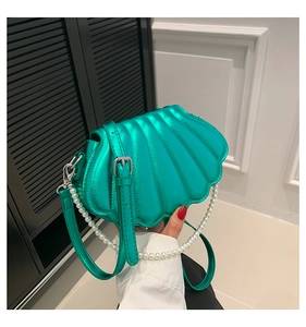 Detail of metallic green shell bag with quilted texture and white pearl chain strap