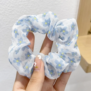 Detailed macro of a blue floral pattern on white mesh scrunchie with soft pleats