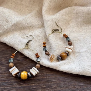 Detailed macro view of bohemian drop earrings with wooden beads and shell on linen