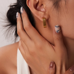 Détail de boucles d'oreilles triple barre plaquées or 18 carats portées par un mannequin