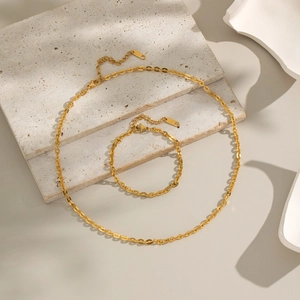 Ensemble collier et bracelet minimaliste doré avec fermoir mousqueton sur marbre