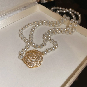 Détail d'un collier de perles double épaisseur avec pendentif camélia doré évidé