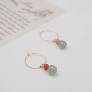 Vintage style gold earrings with pink and light green beads on white background