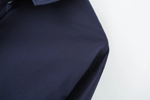 Macro view of navy blue cotton poplin fabric texture and black button detail on shirt