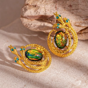 Detailed macro view of gold snake earrings with opal center stone and blue diamond eyes