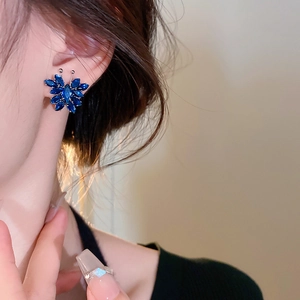 Close-up of elegant butterfly earrings featuring vibrant blue zircon stones on model