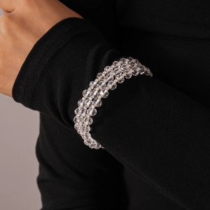 Detail of the triple-layer glass beaded bracelet on a wrist against a dark background