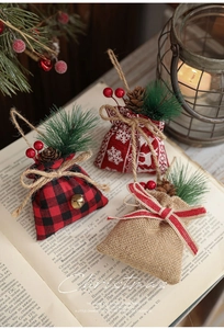 Three Christmas burlap gift bags with pine cones and berries on a vintage book