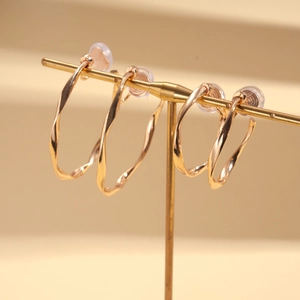 Detailed macro of rose gold geometric twist clip-on earrings with soft silicone pads