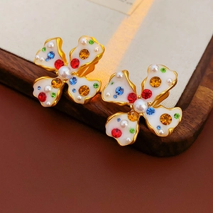 Close-up of vintage flower earrings with white enamel, colorful crystals, and pearls