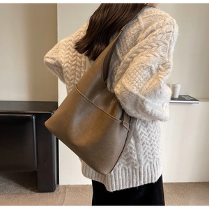 Nahaufnahme einer braunen hobo Schultertasche aus PU-Leder zu einem beigen Pullover