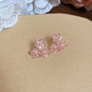 Gros plan de trois boucles d'oreilles cerisier en résine rose sur papier brun