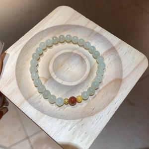Détail d'un bracelet en perles de jade Hetian avec ambre sur un plateau en bois